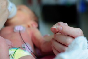 Ett för tidigt fött barn håller sin mammas hand. Foto: Dreamstime