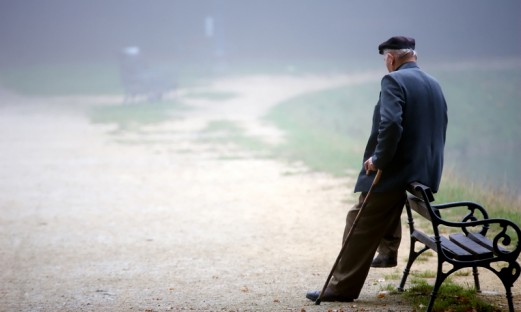 Äldre man som vilar mot en parkbänk