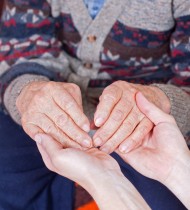En yngre håller en äldre persons händer