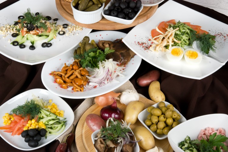 Many food dishes on the restaurant table. Salad dish close up.