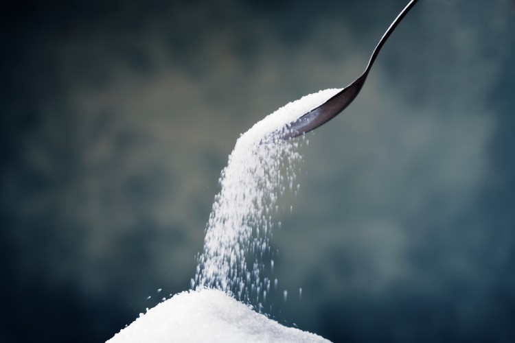 Adding sugar with a spoon.