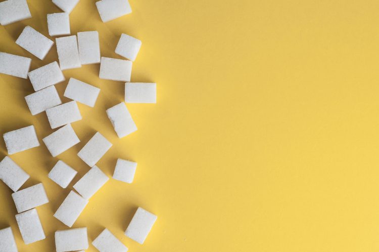 bilden föreställer sockerbitar på ett gult underlag