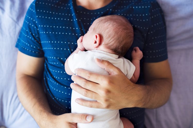 Bilden visar överkroppen på en man som ligger ner och på hans bröst ligger en lite baby. Bilden är tagen upifrån, man ser inte mannens ansikte och bebisen ligger på magen