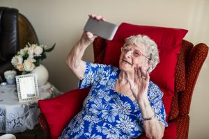 Äldre kvinna video-chattar via sin mobiltelefon.