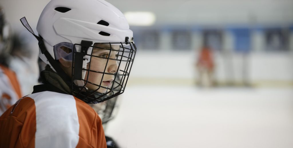 pojke i ishockeyhjälm väntar på att få spela 