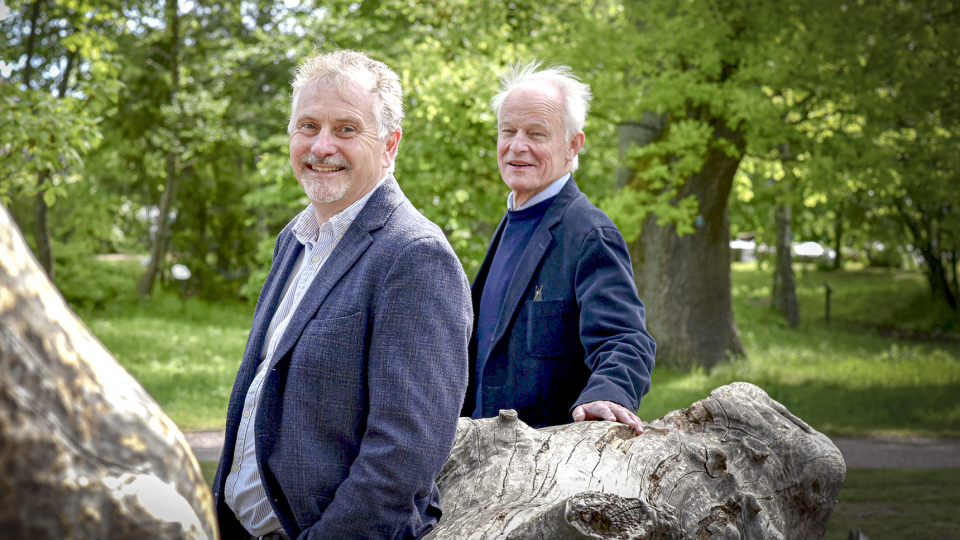 Mårten Segelmark och Lars Björck i en park luar sig på en liggande stam