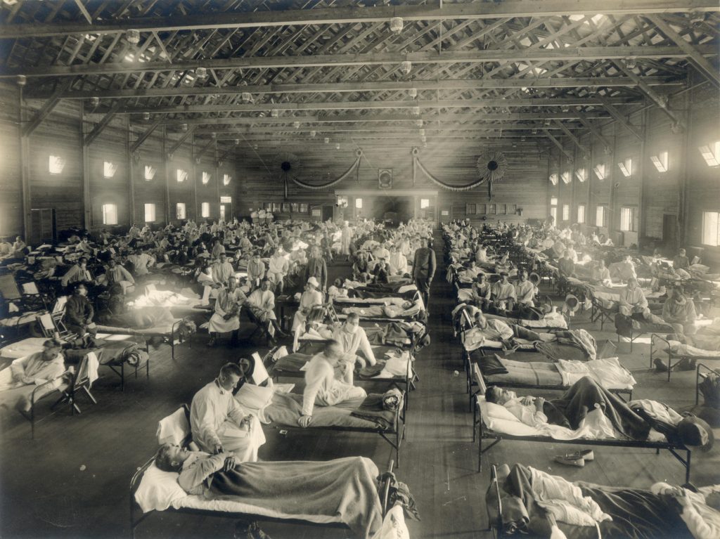 Bild av en jättelik sjuksal med många unga människor liggandes i sjuksängar.