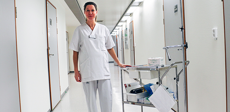 kvinna klädd i vita sjukhuskläder i en sjukhuskorridor. 