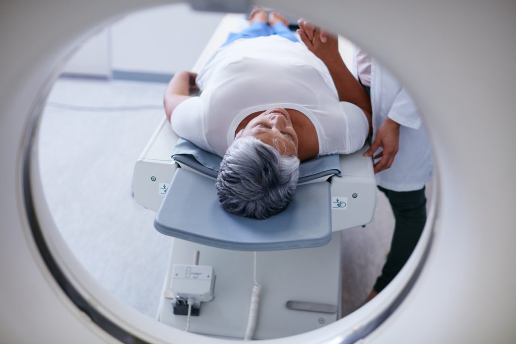patient ligger på brits, redo för att skannas i en datortomograf, en rund ring