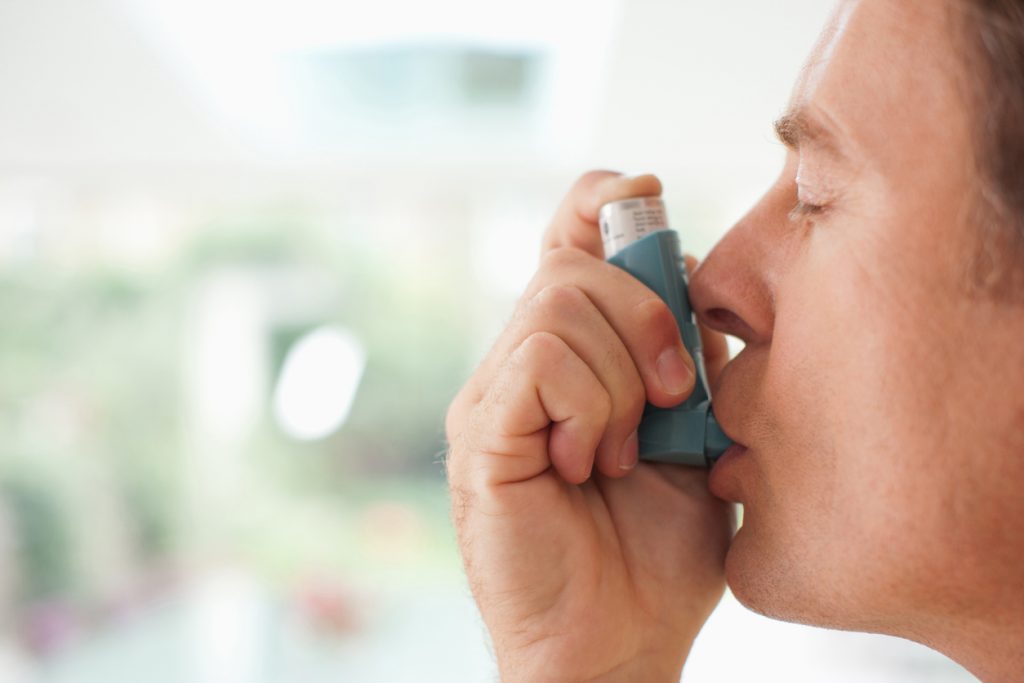 man inhalerar medicin från inhalator