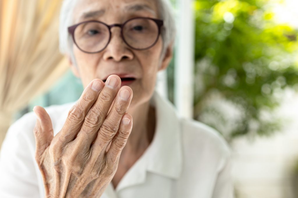 äldre kvinna håller sin hand framför munnen