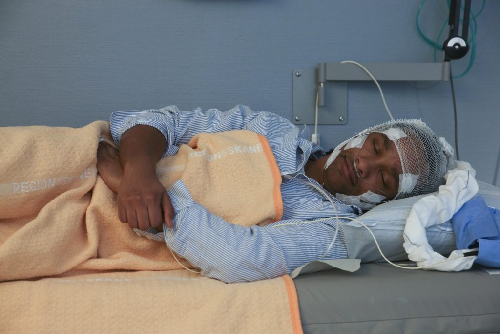 Ungdom sover på sjukhusbrits med elektroder kopplade till huvudet.