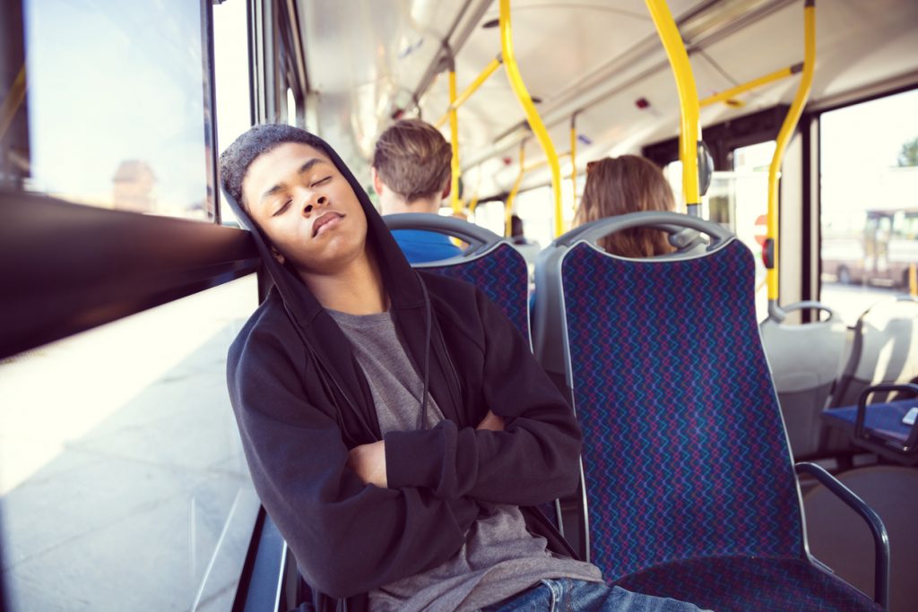 Tonårspojke sover i en buss.