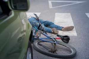 Cykelolycka. Man ser en bil och någons ben på gatan tillsammans med cykel.