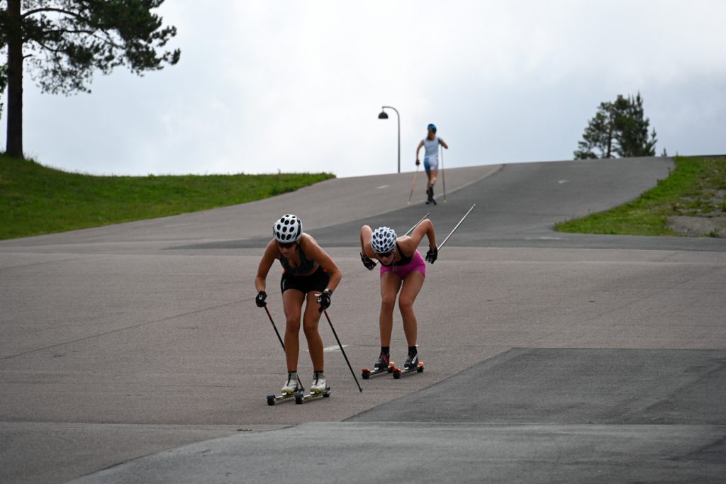 kvinnliga skidåkare tränar på asfalt på rullskidor