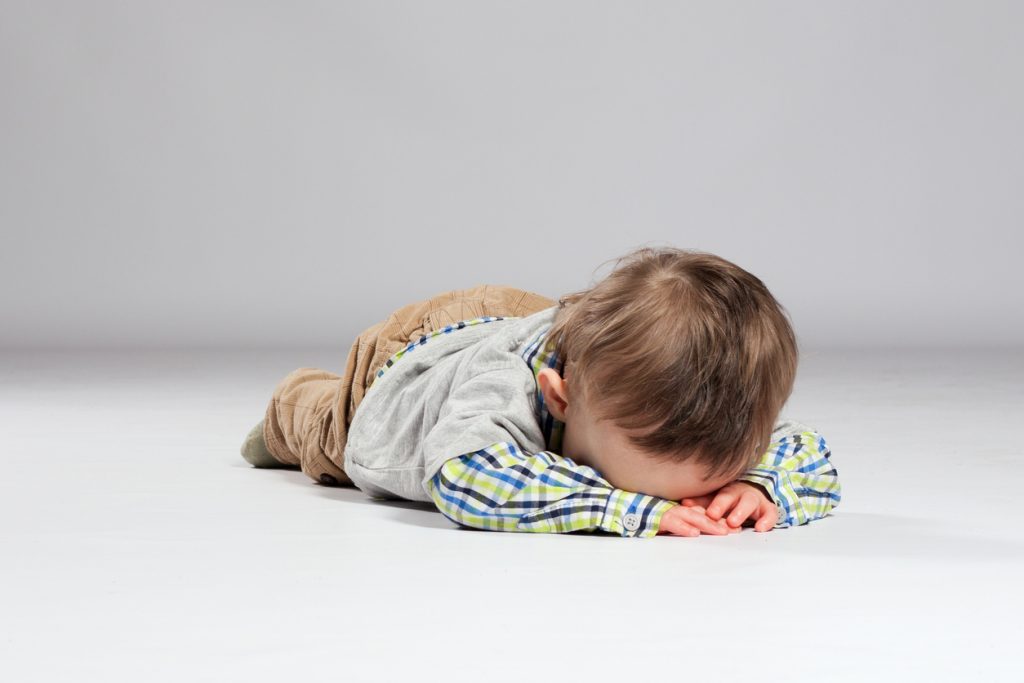 litet barn ligger på golvet med ansiktet nedåt