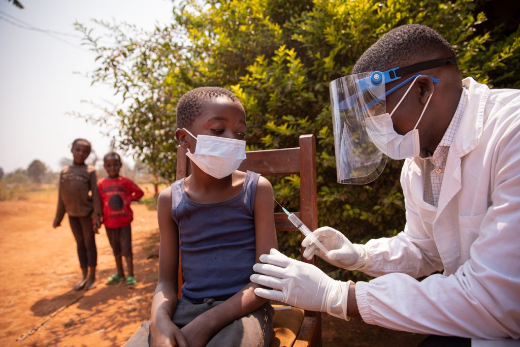 Barn vaccineras utomhus i afrikanskt land.