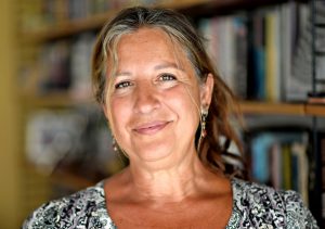 Porträtt av brunögd kvinna med uppsatt hår.