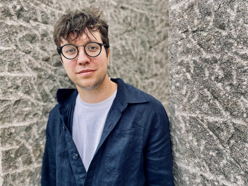 Ung man med rufsigt kort hår och glasögon.