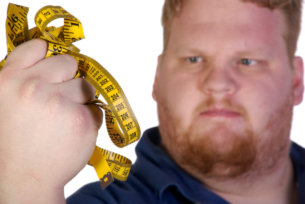 Yngre man med obesitas håller ett mottband i sin hand och ser väldigt bestämd ut